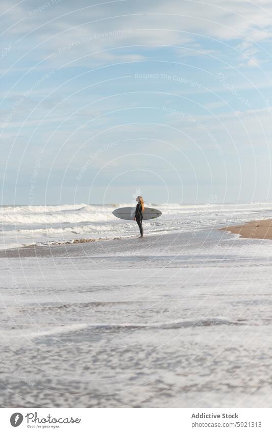 Woman with surfboard standing on wet beach woman coast shore hobby activity pastime sport sea water tide wave waterfront seaside nature seashore equipment