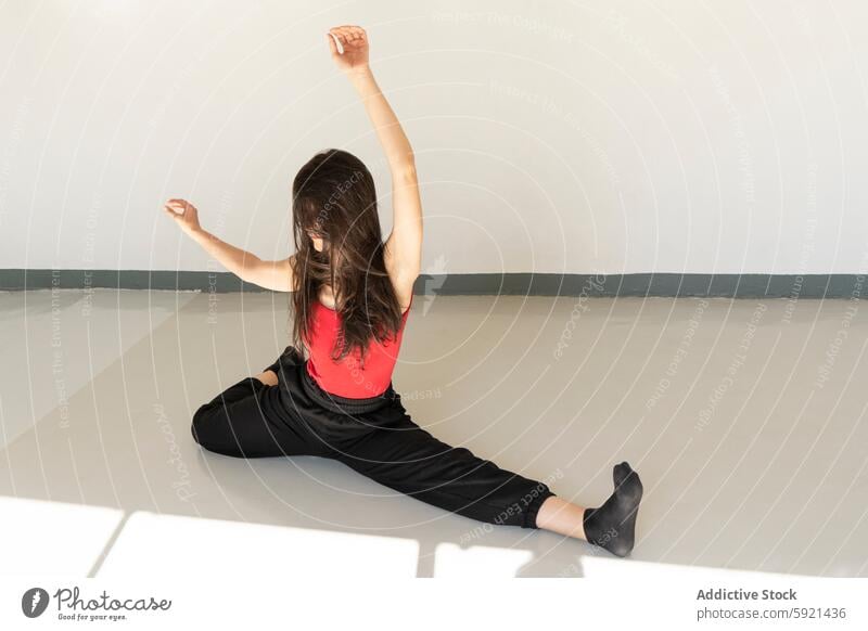 Woman practicing dynamic yoga stretch in serene indoor space woman flexibility tranquility red tank top black pants minimalist health wellness exercise fitness