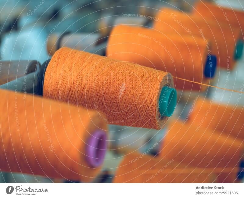 Spools of Orange Yarn in Industrial Textile Production yarn spool factory textile industrial production thread machine manufacturing orange fiber material