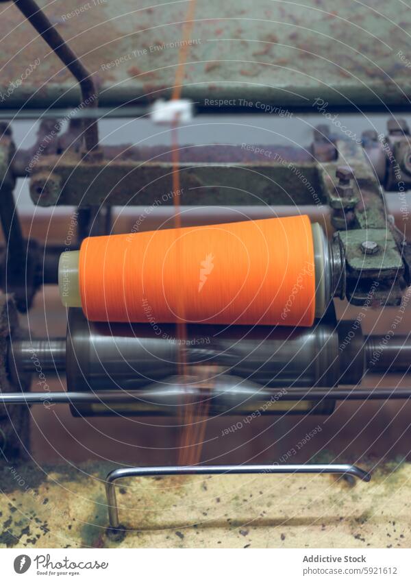 Spinning orange yarn on machinery in textile factory spinning industrial manufacturing plant close-up blurred motion bright equipment production thread fiber