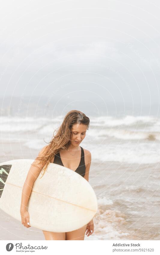 Surfer with surfboard on head on sea beach surfer flying hair sport body swimwear surfing enjoy woman seashore sky thoughtful swimsuit coast stormy ocean