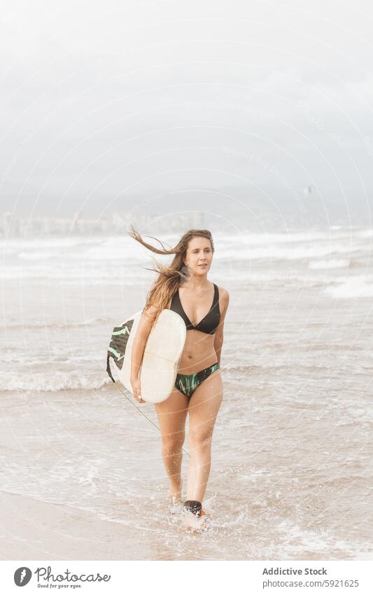 Surfer with surfboard walking on sea beach surfer flying hair sport body swimwear surfing enjoy woman seashore sky swimsuit coast stormy ocean contemplate foamy