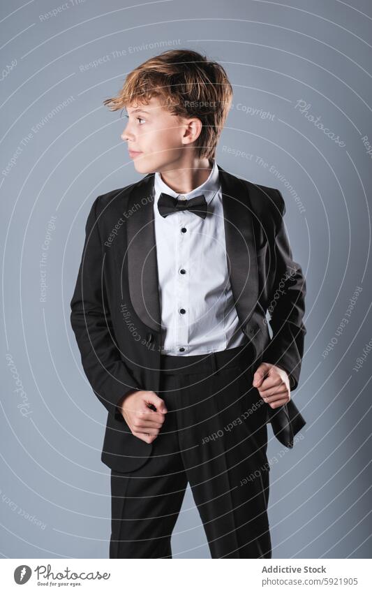 Preteen boy wearing black suit and bow tie looking away in studio formal kid classy elegant confident child style outfit well dressed trendy innocent schoolboy