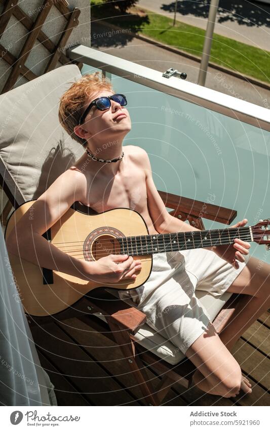 Young musician enjoying guitar on sunny day child playing instrument relaxation summer sunshine outdoor leisure hobby acoustic young boy teenage deck chair