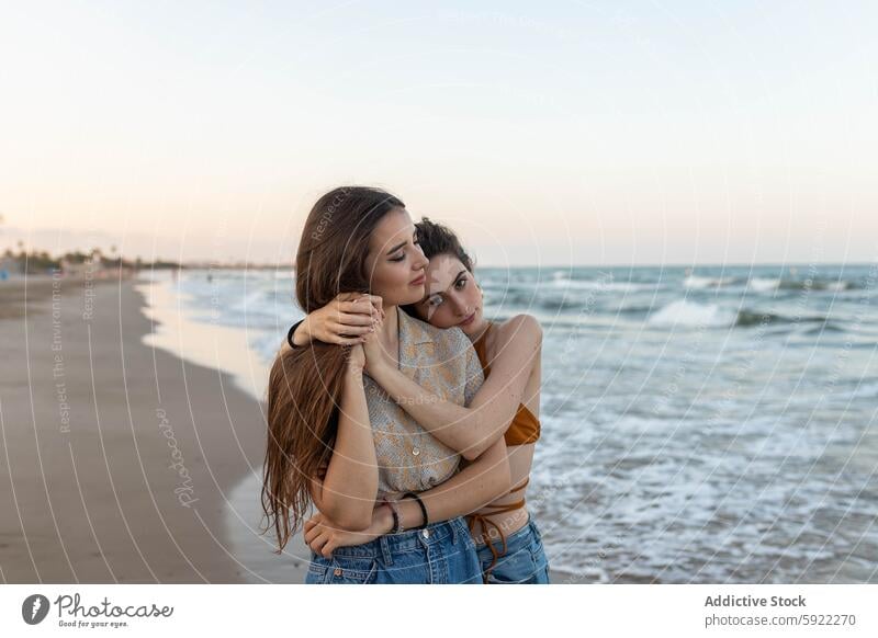 Lesbian couple embracing on beach women lesbian sea sundown hug love date female girlfriend romantic together sunset coast embrace relationship vacation summer