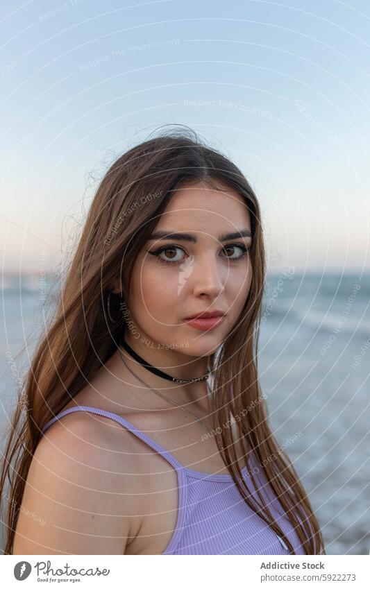 Young woman standing near sea beach wave evening dreamy coast seaside summer weekend female rest young water shore ocean relax long hair wavy hair feminine slim