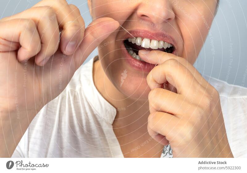 Anonymous close-up image of a person flossing their teeth, emphasizing the importance of dental health and daily hygiene routines oral care gum clean tooth