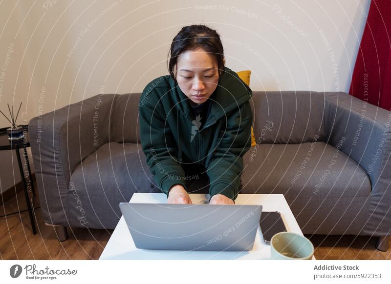 Modern Home Office Setting with Focused Female woman laptop home office work focused technology modern minimalist setting couch comfort casual working remote