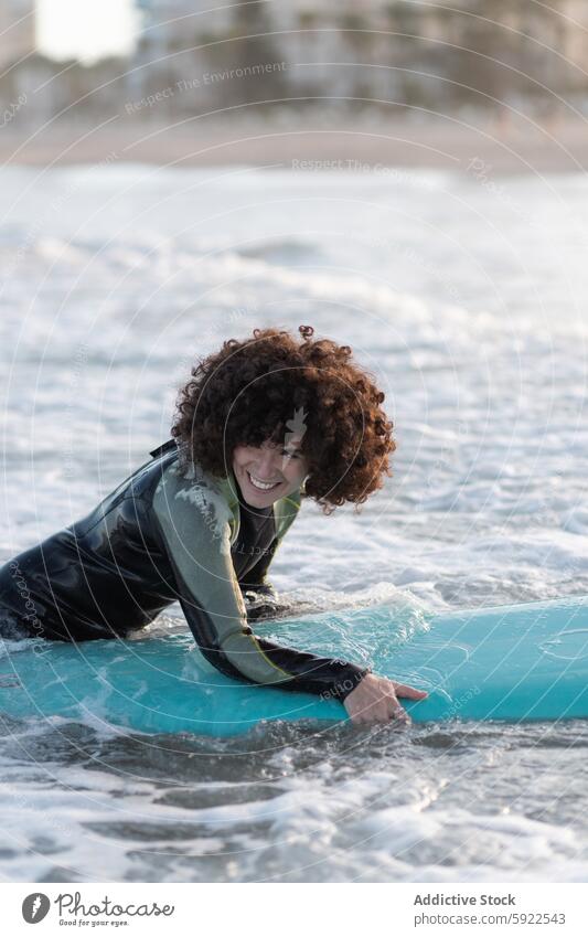 Smiling woman in wetsuit with surfboard in waving sea surfer wave enjoy beach relax foam coast female seawater splash curl afro seacoast summer chill sand