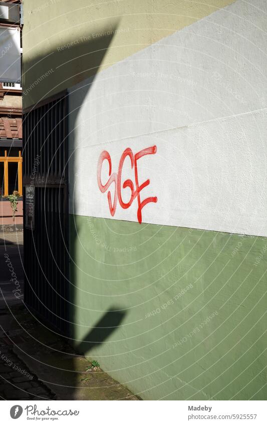 Graffiti with letters in red on the wall of a gateway in natural colors and pastel colors in sunshine in a backyard in Schulstraße in the Sachsenhausen district of Frankfurt am Main in Hesse