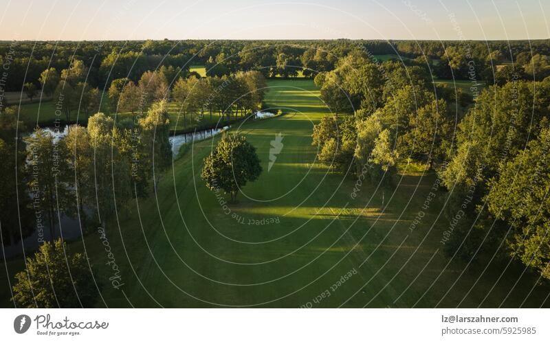 A tranquil aerial view of a lush golf course fairway, bathed in the warm glow of sunset. Ideal for themes of relaxation, nature, and sports, this image captures the peaceful beauty of the golfing experience.