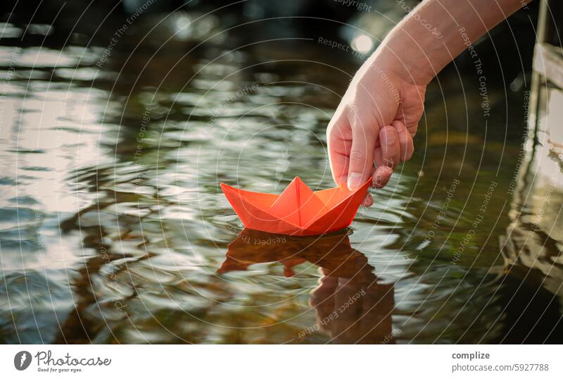 Small red paper ship is put into a lake by a boy Paper boat Target Sailing ship Navigation Beach River bank coast Lakeside Waves Nature Water Environment Child