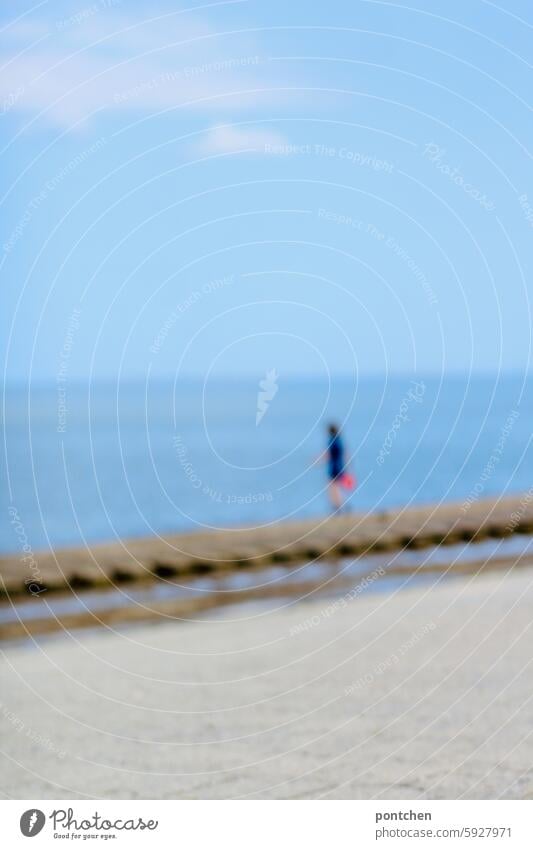 a child in uv-protective clothing stands in the sea. blurred hazy blurriness Anonymous Joy vacation Ocean untroubled Exterior shot Relaxation Vacation & Travel