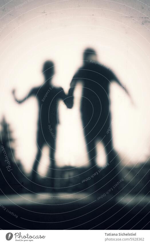 Silhouette of two children holding hands Shadow Shadow play Structures and shapes Exterior shot hazy blurriness