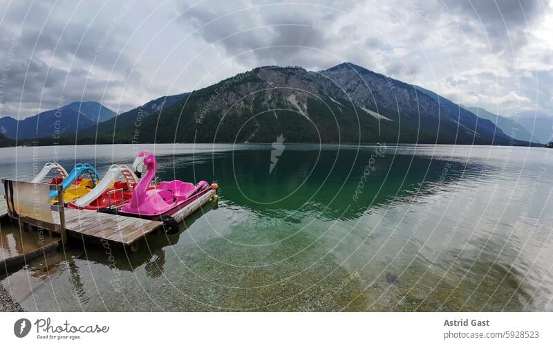 Bunte Tretboote auf dem Plansee in Österreich mit dunkler Wolkenstimmung plansee gewässer steg tretboote gebirge berge österreich bergsee wasser himmel wolken