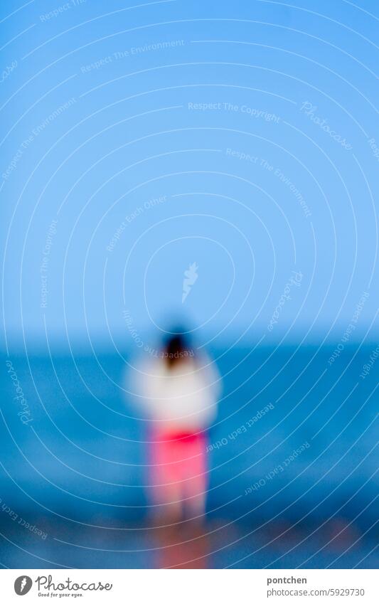 a woman looks at the sea. rear view, blurred Woman Ocean tranquillity hazy Blue Water Nature Relaxation coast Beach Tourist vacation North Sea Landscape