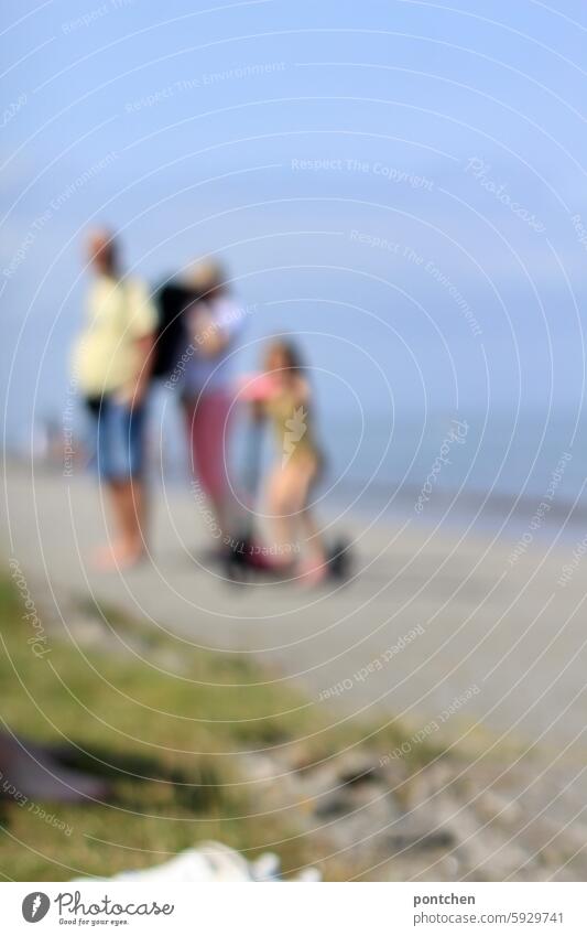 two adults and a child in swimwear on a scooter by the sea. blurred Child hazy blurriness Anonymous Joy vacation Ocean untroubled Driving pink Mobility