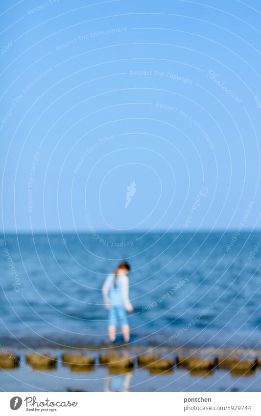 a child in uv-protective clothing stands in the sea. blurred hazy blurriness Anonymous Joy vacation Ocean untroubled Exterior shot Relaxation Vacation & Travel