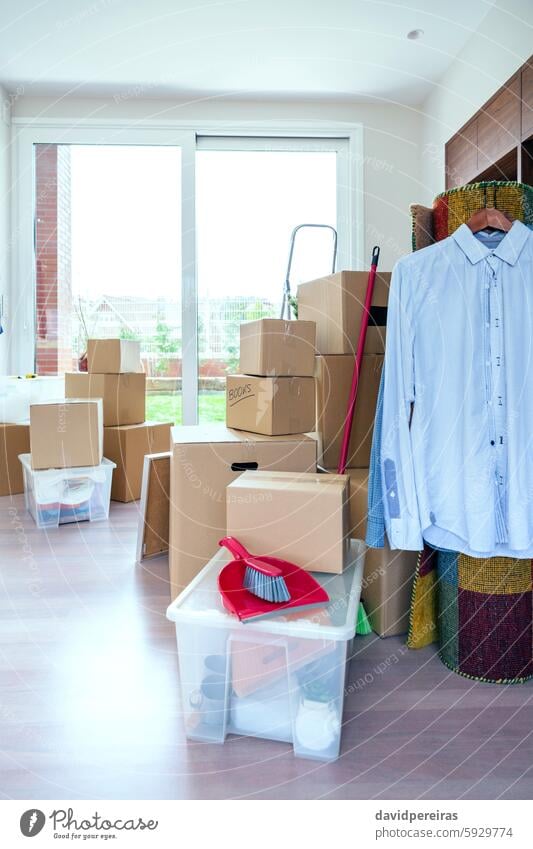 Living room with moving boxes brand new home move relocation clothes shirt dustpan picker broom stack pile packing house living prepare place apartment property