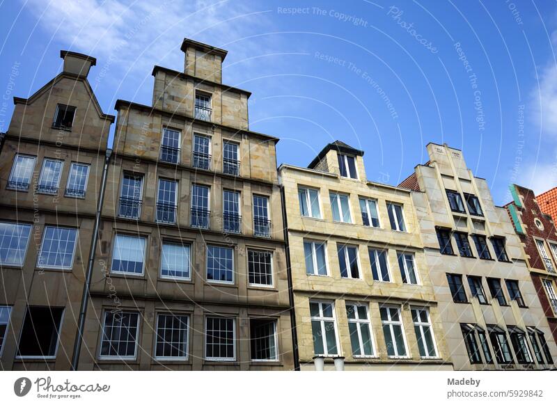 Beautiful old merchant's house and old building with stepped gable in beige and natural colors in front of a blue sky in the sunshine at Prinzipalmarkt in the city and old town of Münster in Westphalia in Münsterland