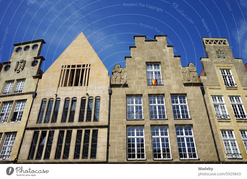 Beautiful old merchant's house and old building with stepped gable in beige and natural colors in front of a blue sky in the sunshine at Prinzipalmarkt in the city and old town of Münster in Westphalia in Münsterland