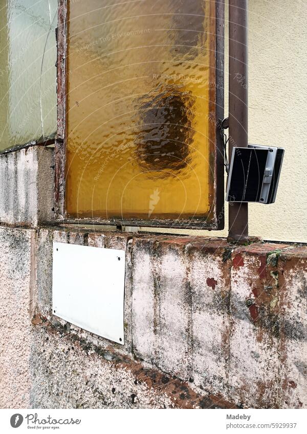 Windows made of ribbed glass with yellow coloring and modern monitoring technology of an old residential building in the district of Gleiberg in Wettenberg Krofdorf-Gleiberg near Gießen in Hesse