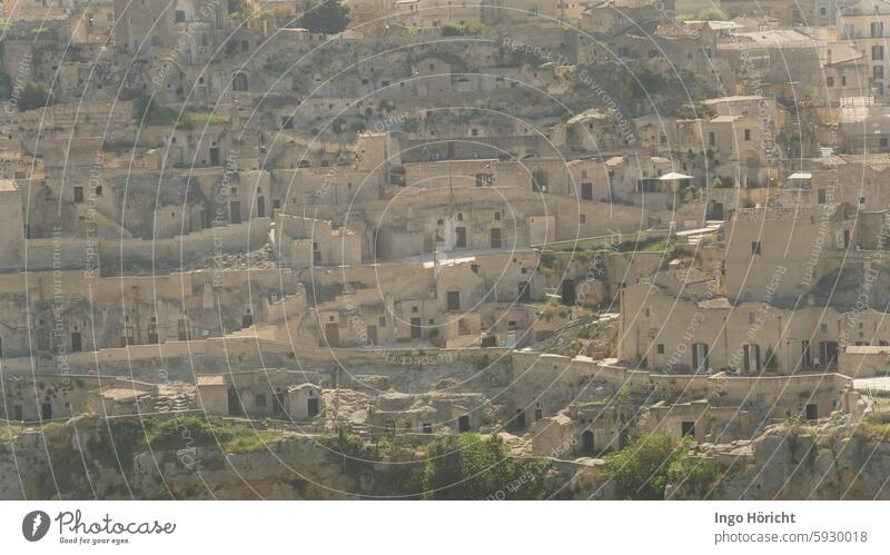 View of the old town of Matera (southern Italy) which stretches up a hill. The entire surface of the photo is filled with ancient houses made of natural stone, no sky. The houses appear abandoned and deserted.