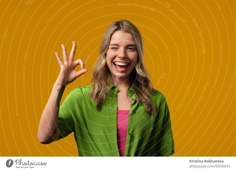 Pretty woman with OKAY sign, ok gesture. Happy lady, correct choice, yellow wall good okay yes agreement hand satisfaction symbol approve leisure lifestyle