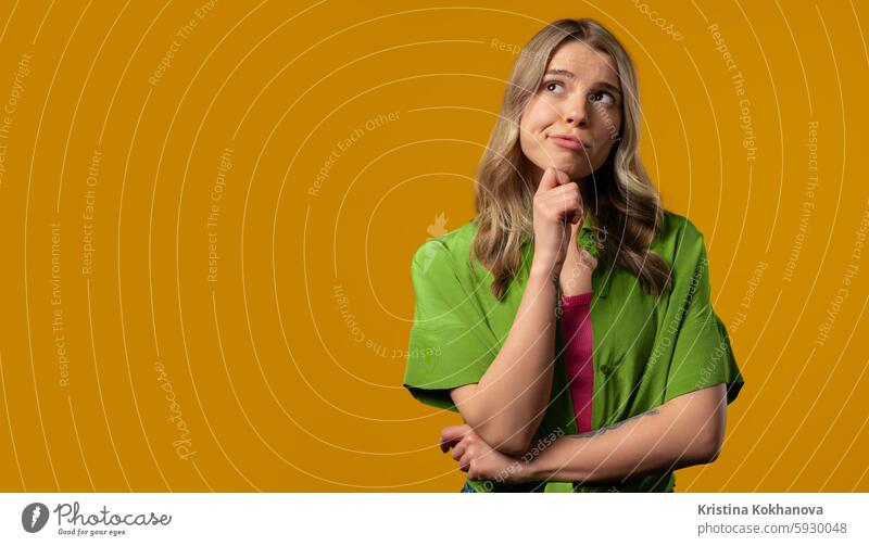 Thinking around stylish woman on yellow background. Puzzled lady looking answer adult casual caucasian cheerful confident eureka expression face finger genius