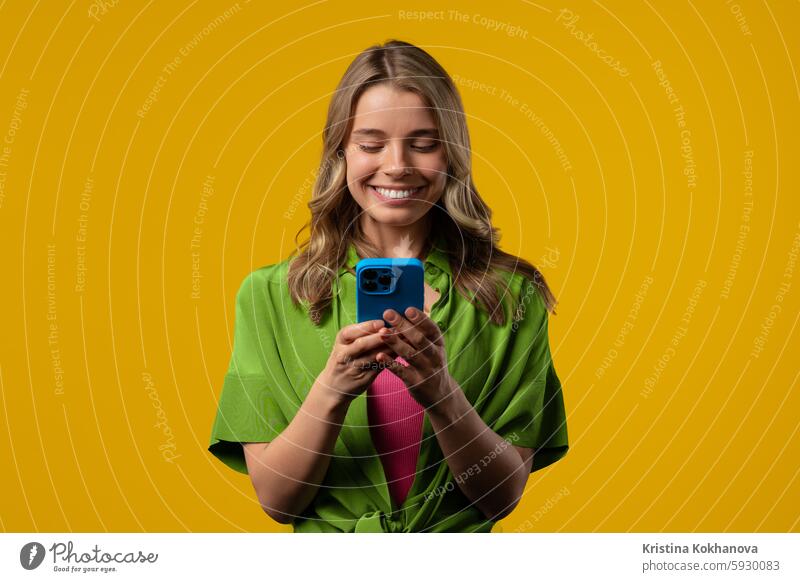 Pretty woman surfing internet on smartphone.Girl with smile on yellow background adult app boy call carefree caucasian cellphone communication confidence