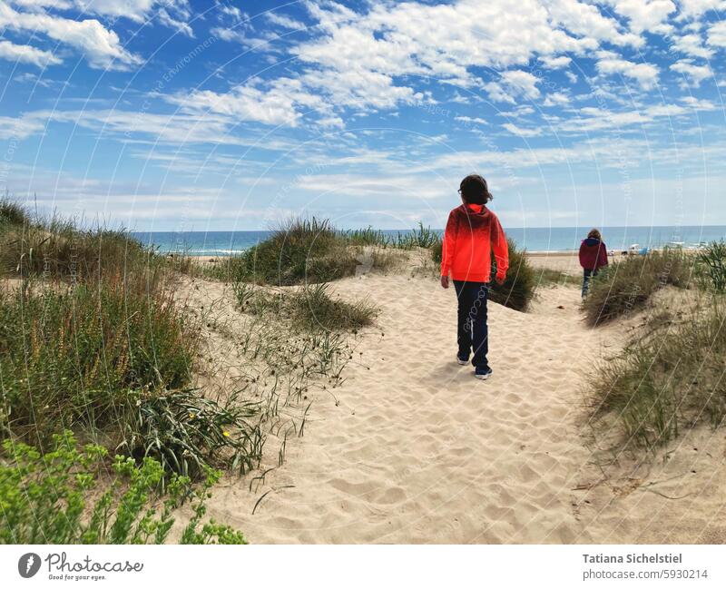 Boy with orange sweater walking on sand in the dunes towards the sea Ocean Boy (child) Child Sand Sandy beach Sky Orange Vacation & Travel coast Relaxation