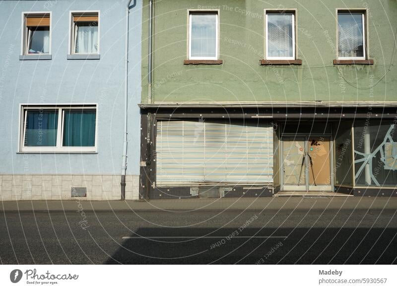 Vacant store with old blinds, emergency glazing and cracked shop window with adhesive tape in the sunshine on Krofdorfer Straße in Giessen in Hesse at home