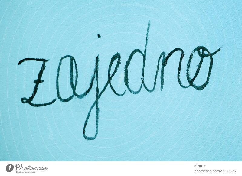 zajedno (together) in black handwriting on a blue wall Croatian in common togetherness at the same time cursive Together Attachment Teamwork Friendship