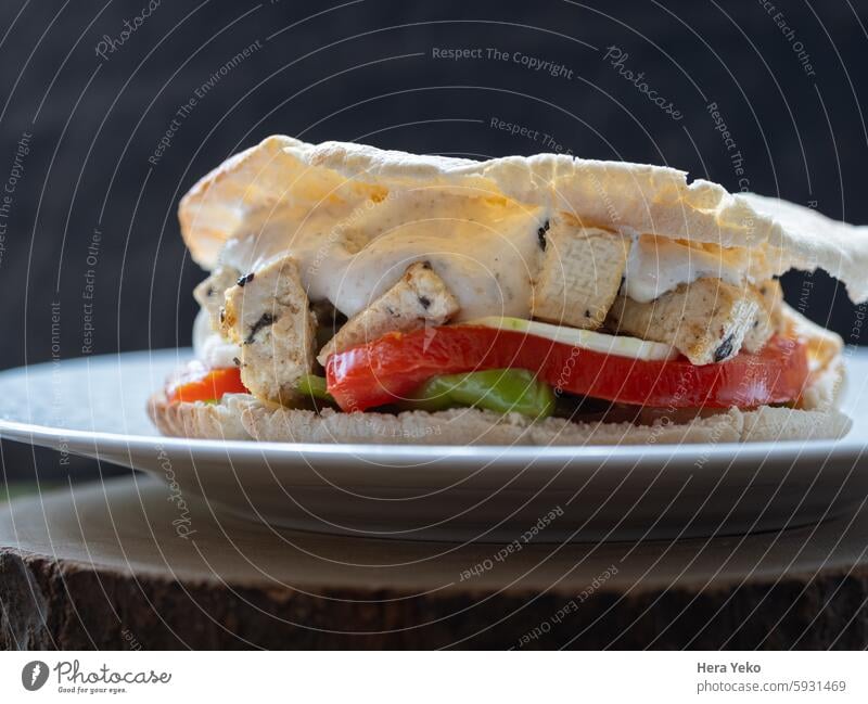 Vegetarian vegetable and tofu sandwich with yogurt sauce. black background snack vegetarian vegetables tomato pepper cucumber pita bread wood white daylight