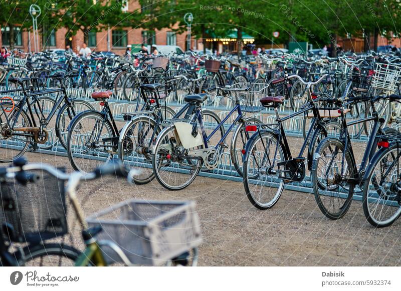 Many bicycles parked at a public bike rack in Copenhagen city parking street commuting copenhagen cycling eco friendly transportation urban sidewalk traditional