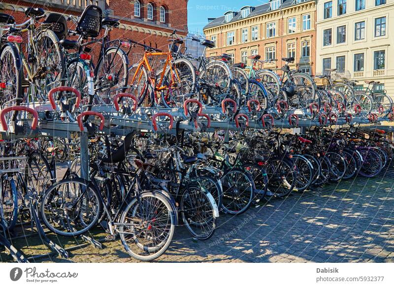 Many bicycles parked at a public bike rack in Copenhagen city parking street commuting copenhagen cycling eco friendly transportation urban sidewalk traditional