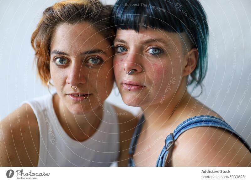 Intimate portrait of two sisters with expressive eyes expression gaze nose piercing emotion connection adult facial feature hair hair color close-up direct look