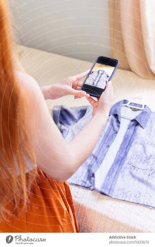 Anonymous woman photographing shirt for online sale smartphone photography wardrobe decluttering digital marketing e-commerce secondhand recycle fashion