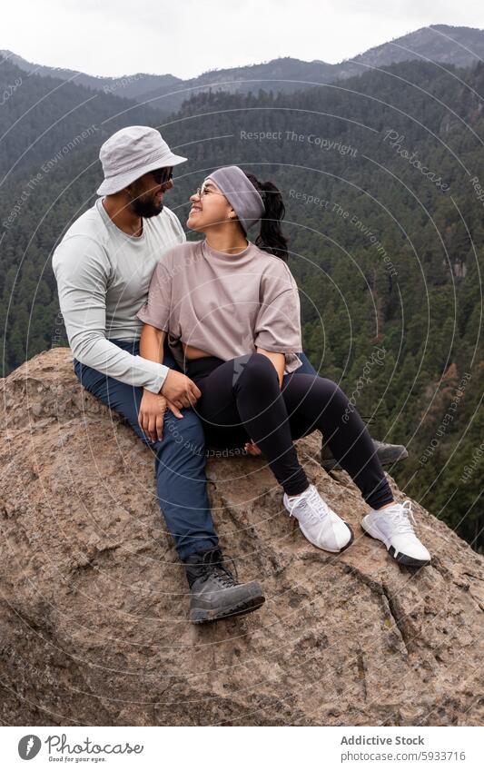 Couple smiling at each other on a mountain hike forest hiking couple man woman love outdoor adventure nature togetherness sitting rock landscape green peaceful