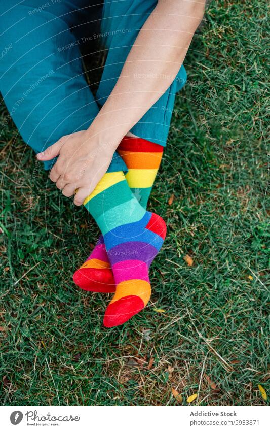 Person wearing colorful lgbt rainbow socks sitting on green grass person lesbian teal pantal outdoor comfort casual relaxed vibrant playful style fashion cozy