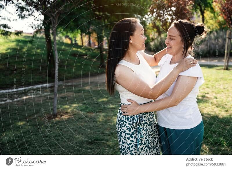 Two lesbian colombian women embracing and smiling in a park with greenery woman lgbt couple embrace smile nature outdoor friendship affection joy happiness love