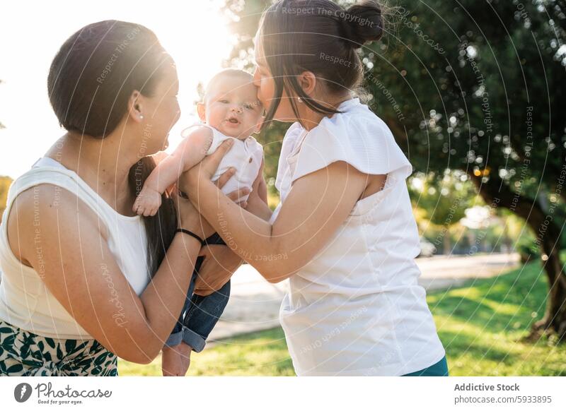 Lesbian couple kissing young son on a sunny day outdoors lesbian baby family mother same-sex love joy infant parent modern happiness engagement togetherness