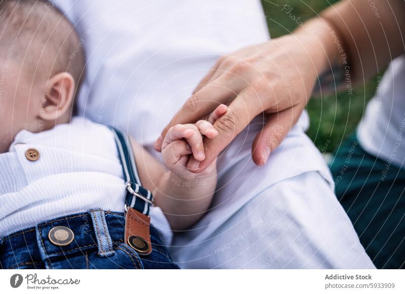 Tender moment between lesbian couple and their son family love unity tenderness touch hand finger grip child mother bonding close-up care relationship parenting