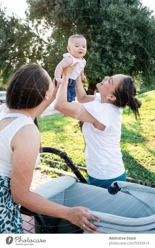 Lesbian couple and their son enjoying outdoor playtime lesbian family park sunny love happiness child lifting air moment smile fun bonding relationship