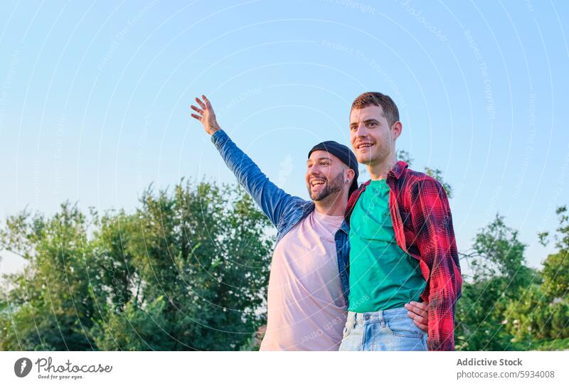 Gay couple enjoying a sunny day outdoors together gay men nature sky gesture smiling happy love relationship happiness affection bond leisure casual clothing