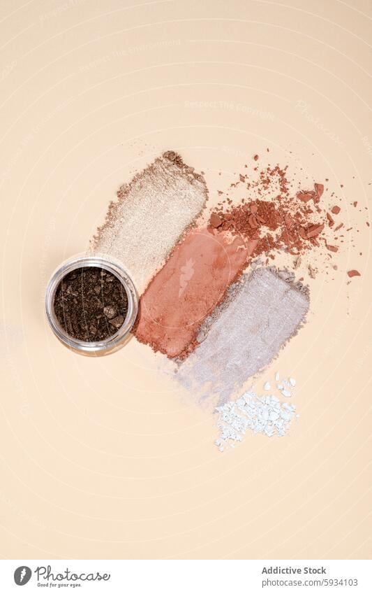 Top view of assorted crushed eyeshadows on beige background top view makeup texture cosmetic neutral tone jar spread powder beauty fashion glamour palette