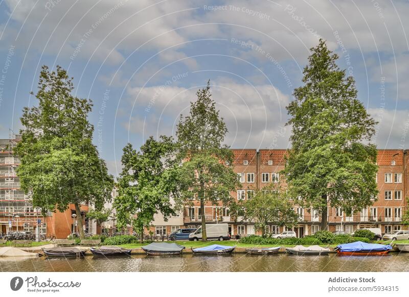 Scenic canal view with moored boats and residences residential building sky cloud tree waterway serene urban nature outdoor architecture cityscape travel scenic