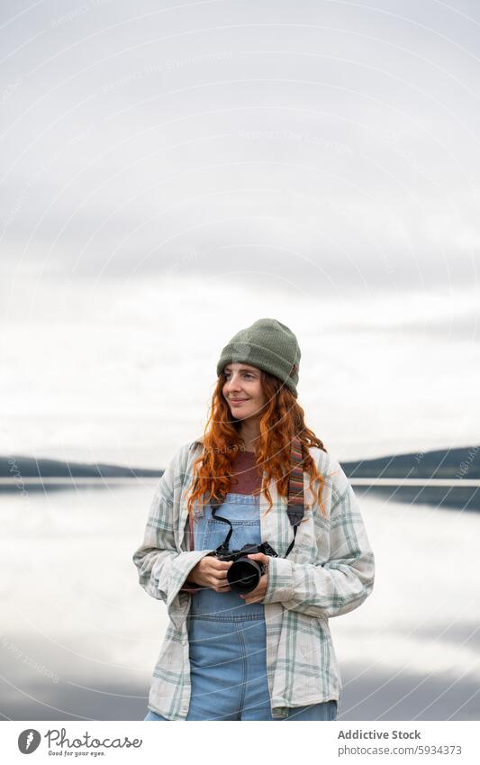 Outdoor photographer captures serene lakeside moments woman camera outdoor casual apparel focus expression nature landscape waterscape calm peaceful denim