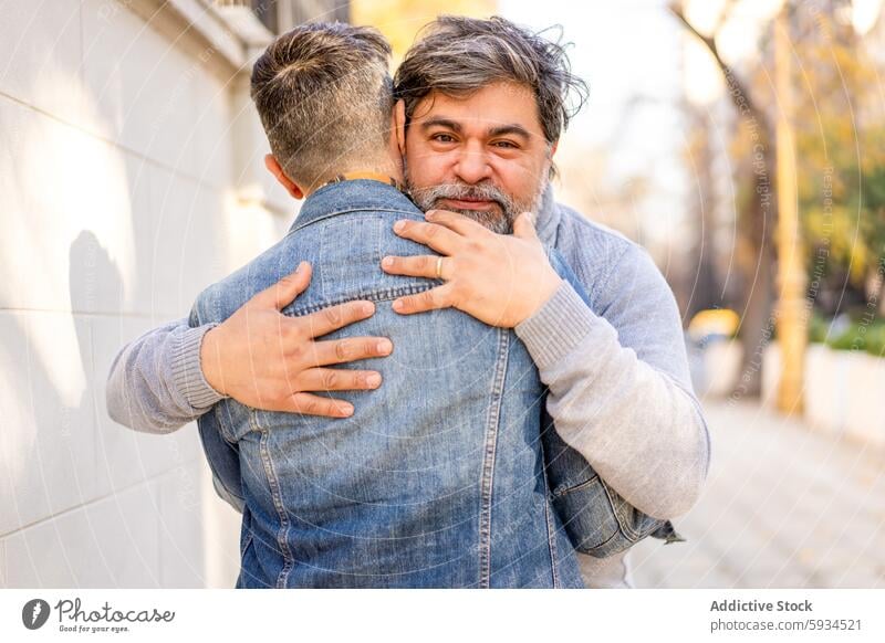 Gay couple embracing lovingly on a sunny day gay embrace hug love affection togetherness outdoor street city romantic connection relationship men adult mature