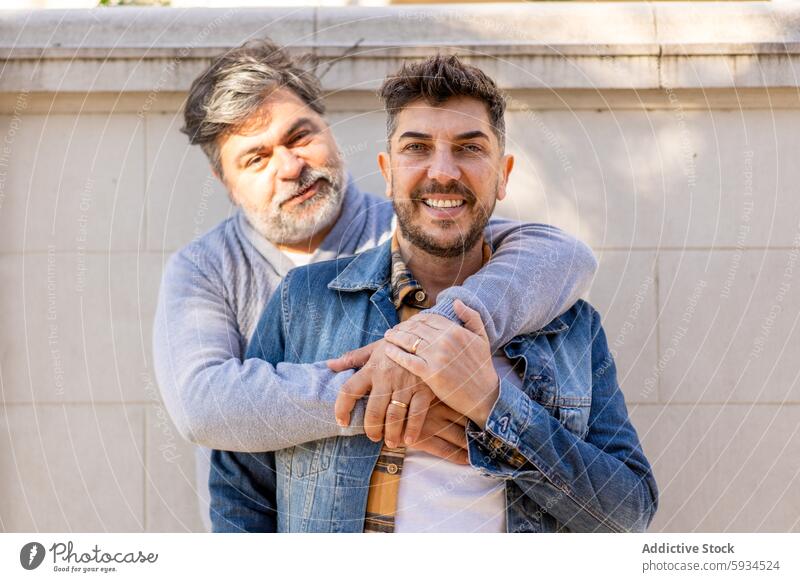 Gay couple enjoying a sunny day outdoors gay affectionate joyful smile happy hugging men sunlight casual clothing love relationship mature adult partner